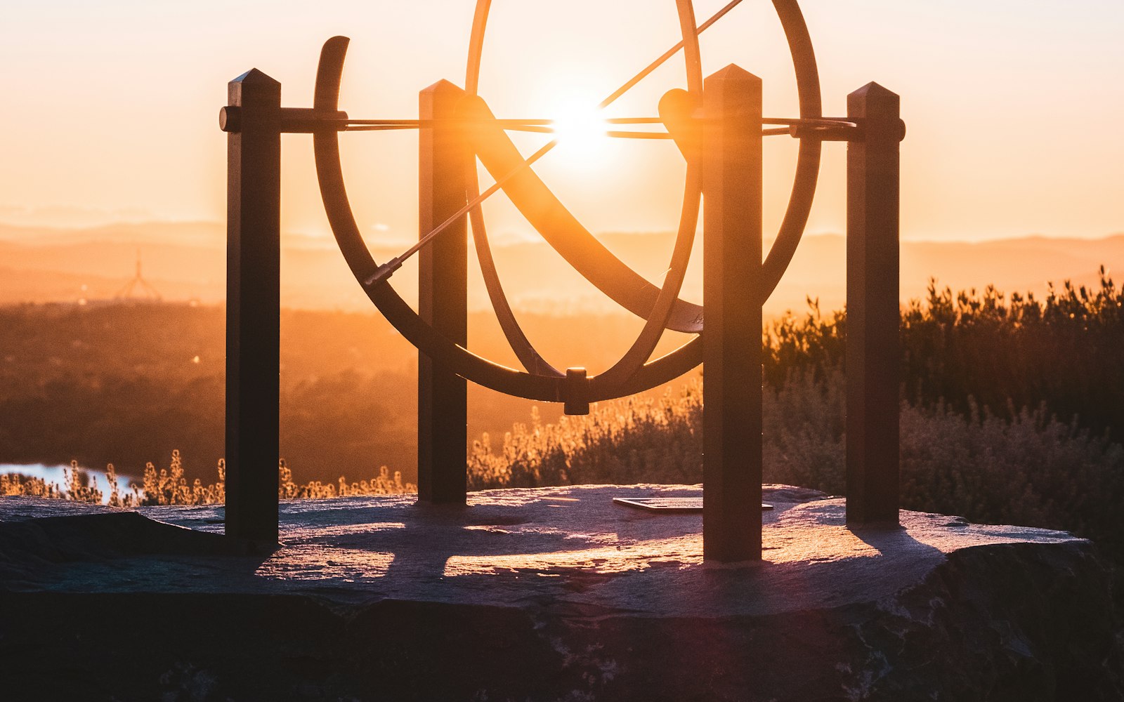 Dramatic sunset with a large metal astronomical sphere sculpture overlooking the landscape